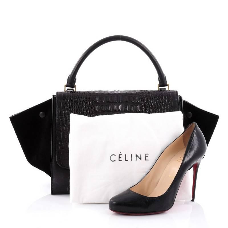 This authentic Celine Trapeze Handbag Crocodile and Leather Medium is a fashionista's dream bag. Crafted from genuine black crocodile and black leather with black suede wings, this bag features top rolled leather handle, side wings snap closures,