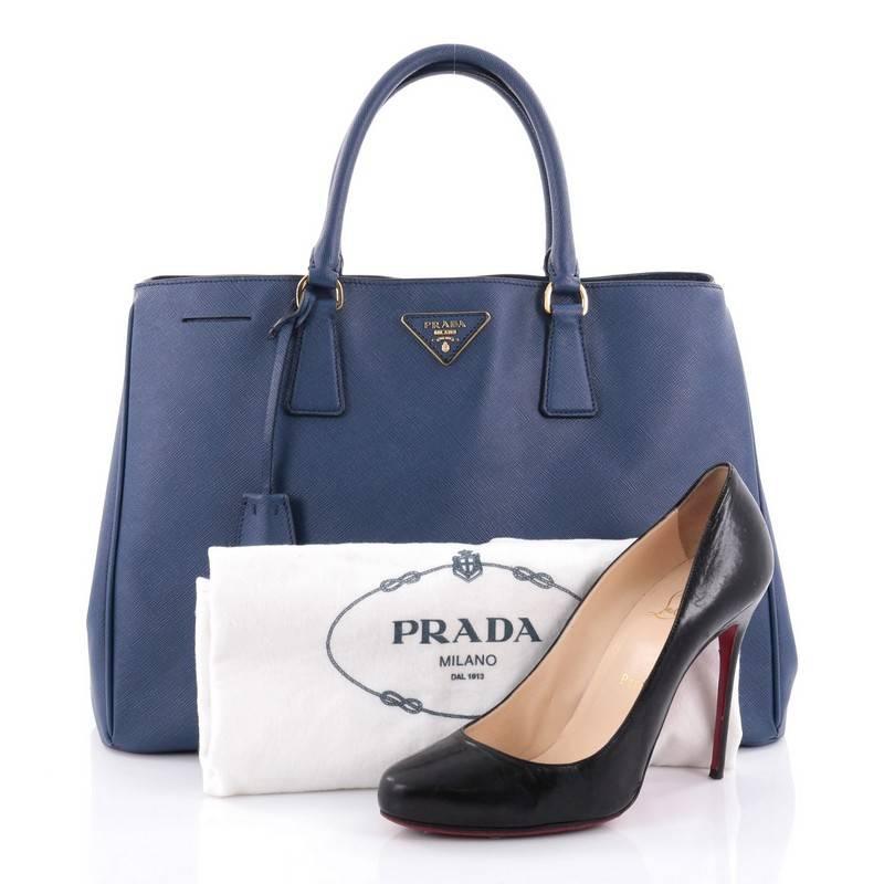 This authentic Prada Lux Open Tote Saffiano Leather Medium is elegant in its simplicity and structure. Crafted from blue saffiano leather, this sturdy and spacious tote features dual-rolled handles, gusseted side with snap buttons, iconic Prada logo