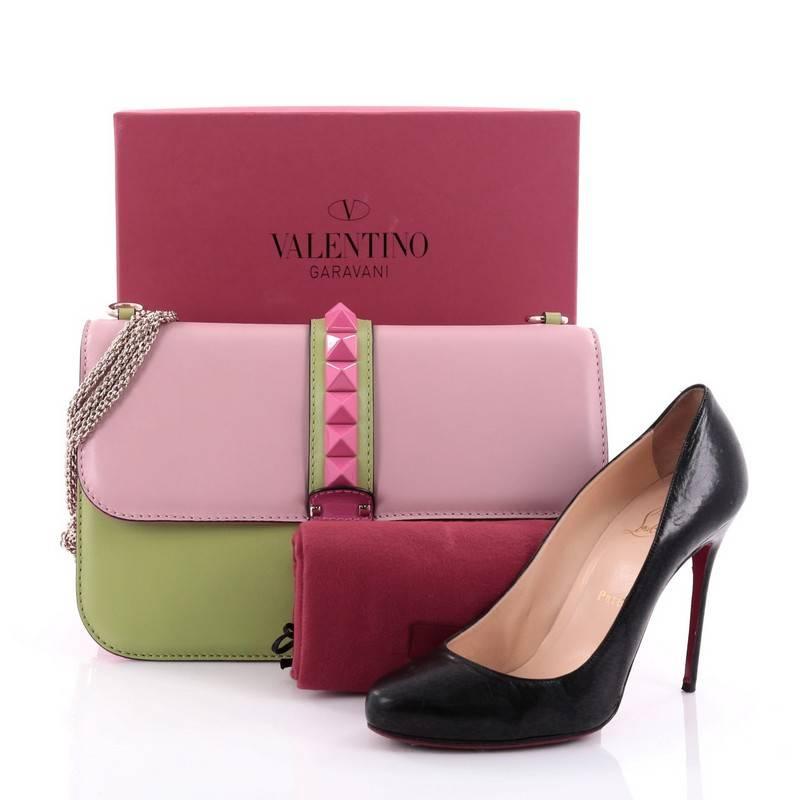 This authentic Valentino Glam Lock Shoulder Bag Leather Large is a fun, exciting and bold accessory perfect for nights out. Crafted from pink and green leather, this beautiful flap bag features a long gold-tone chain strap that allows it to be worn