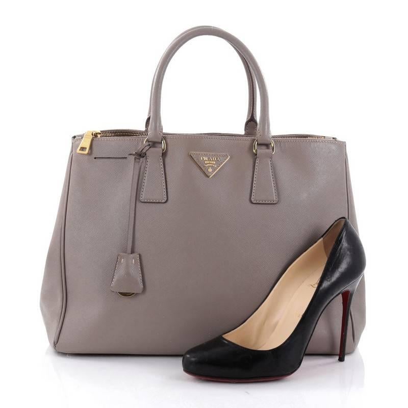 This authentic Prada Double Zip Lux Tote Saffiano Leather Medium is the perfect bag to complete any outfit. Crafted from light brown saffiano leather, this boxy tote features side snap buttons, raised Prada logo, dual-rolled leather handles and