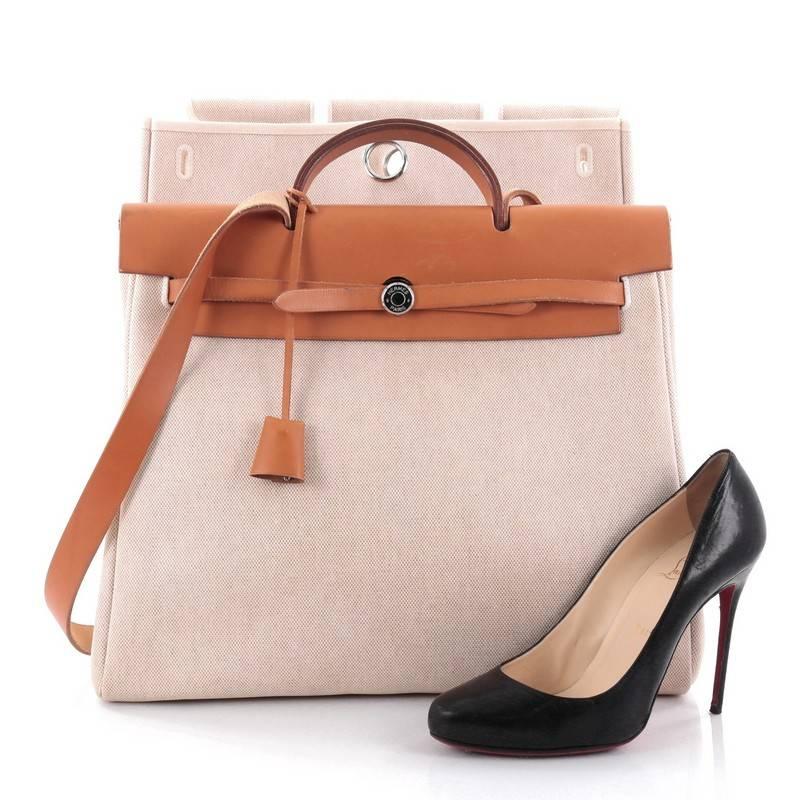 This authentic Hermes Herbag Toile and Leather GM is a fabulously functional, lightweight tote made for everyday excursions. Constructed from natural canvas and tan leather, this versatile tote features a flat leather top handle, palladium hidden
