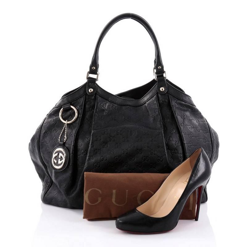 This authentic Gucci Sukey Tote Guccissima Leather Large is a chic tote ideal for your everyday wear. Crafted from black guccissima leather, this pleated tote with a ring charm accent features dual-rolled leather top handles, side snap buttons, and