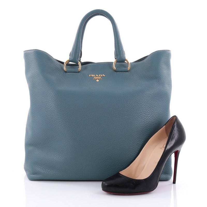 This authentic Prada Shopper Tote Vitello Daino Large exudes a stylish and industrial design made for everyday excursions. Crafted from light blue vitello daino leather, this tote features dual-rolled leather handles, raised gold Prada Milano logo,