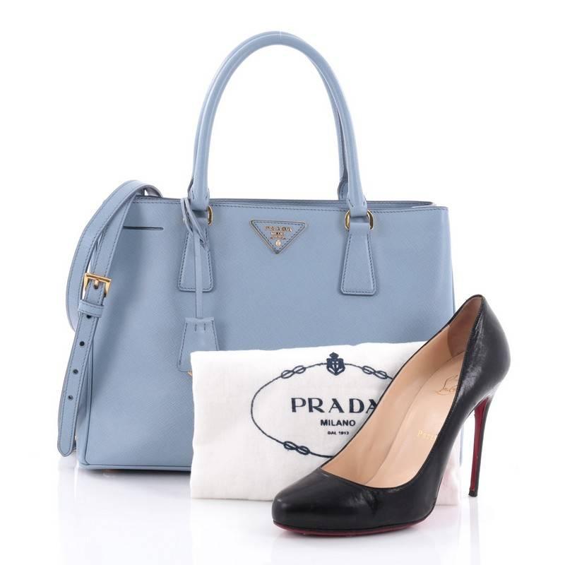 This authentic Prada Gardener's Tote Saffiano Leather Medium is elegant in its simplicity and structure. Crafted from light blue saffiano leather, this tote features dual-rolled leather handles, raised Prada logo, protective base studs, and