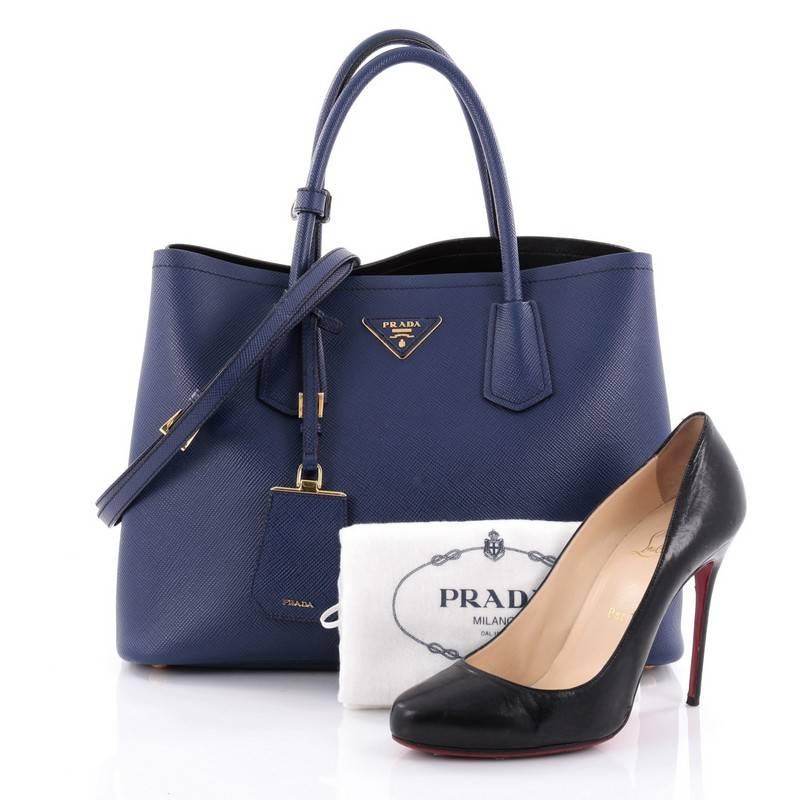 This authentic Prada Cuir Double Tote Saffiano Leather Medium is elegant in its simplicity and structure. Crafted from sturdy blue saffiano leather, this tote features dual-rolled handles, side snap buttons, Prada's trademark triangle logo at the