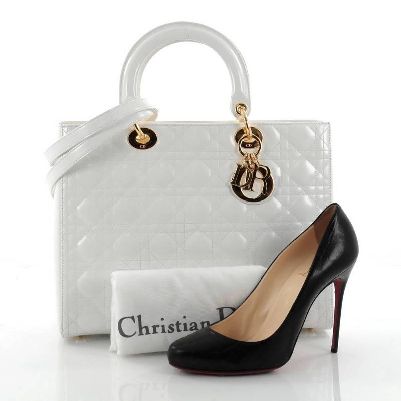 This authentic Christian Dior Lady Dior Handbag Cannage Quilt Patent Large is a classic staple that every fashionista needs in her wardrobe. Crafted from white patent leather in Dior's iconic cannage quilting, this boxy bag features dual-rolled