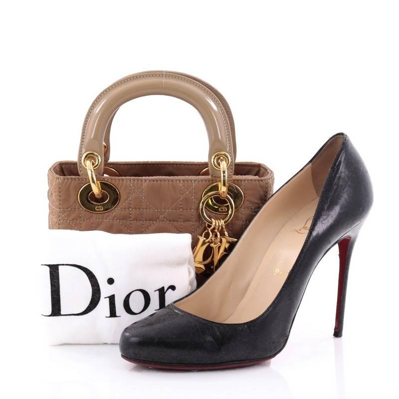 This authentic Christian Dior Lady Dior Handbag Cannage Quilt Nylon Mini is an elegant classic bag that every fashionista needs in her wardrobe. Crafted from brown nylon in Dior's iconic cannage quilting, this top handle bag features short dual