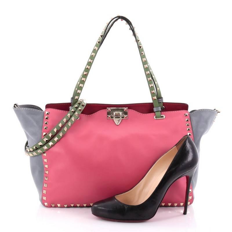 This authentic Valentino Colorblock Rockstud Tote Soft Leather Medium mixes edgy style with luxurious detailing. Crafted from pink and grey soft leather, this stylish tote features dual tall flat handles, gold-tone pyramid stud trim details, a