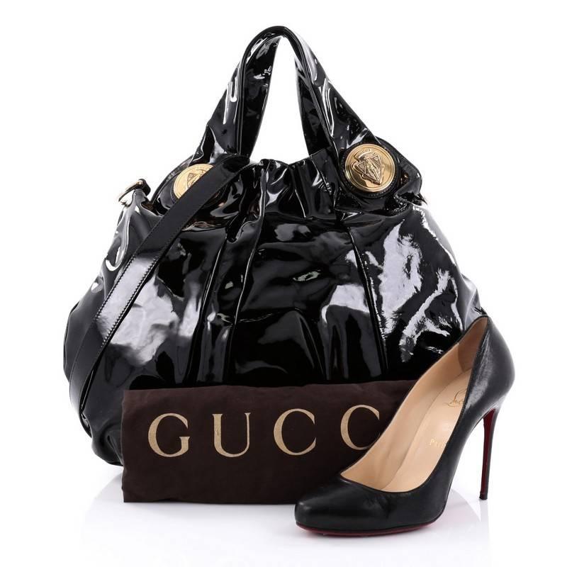 This authentic Gucci Hysteria Convertible Top Handle Bag Patent Large is a lovely accessory for any Gucci lover showcasing a casual yet elegant design. Crafted from black patent leather, this luxurious hobo showcases dual shoulder straps with