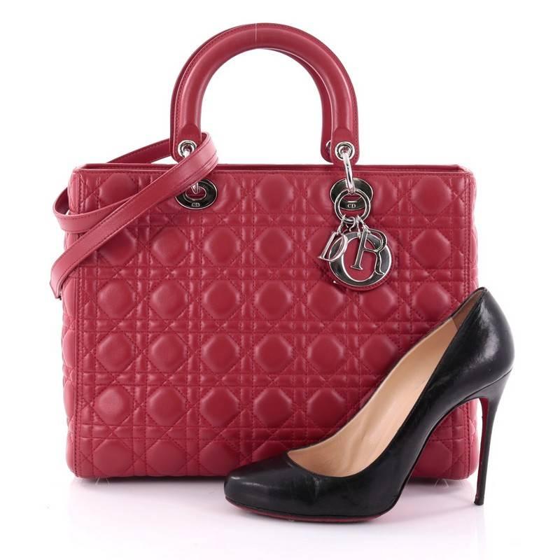 This authentic Christian Dior Lady Dior Handbag Cannage Quilt Lambskin Large is a classic staple that every fashionista needs in her wardrobe. Crafted from red lambskin leather in Dior's iconic cannage quilting, this boxy bag features dual-rolled