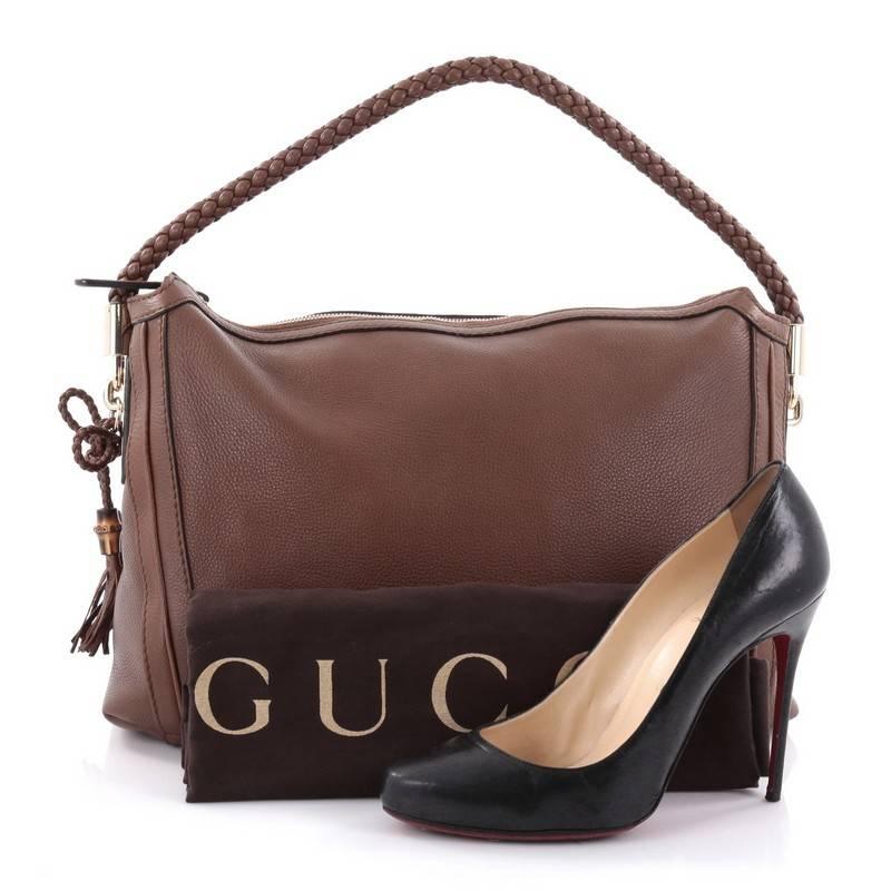 This authentic Gucci Bella Hobo Leather Medium is your perfect everyday bag. Crafted in brown leather, this hobo features single loop braided handle, side tassels, protective base studs and gold-tone hardware accents. Its top zip closure opens to a
