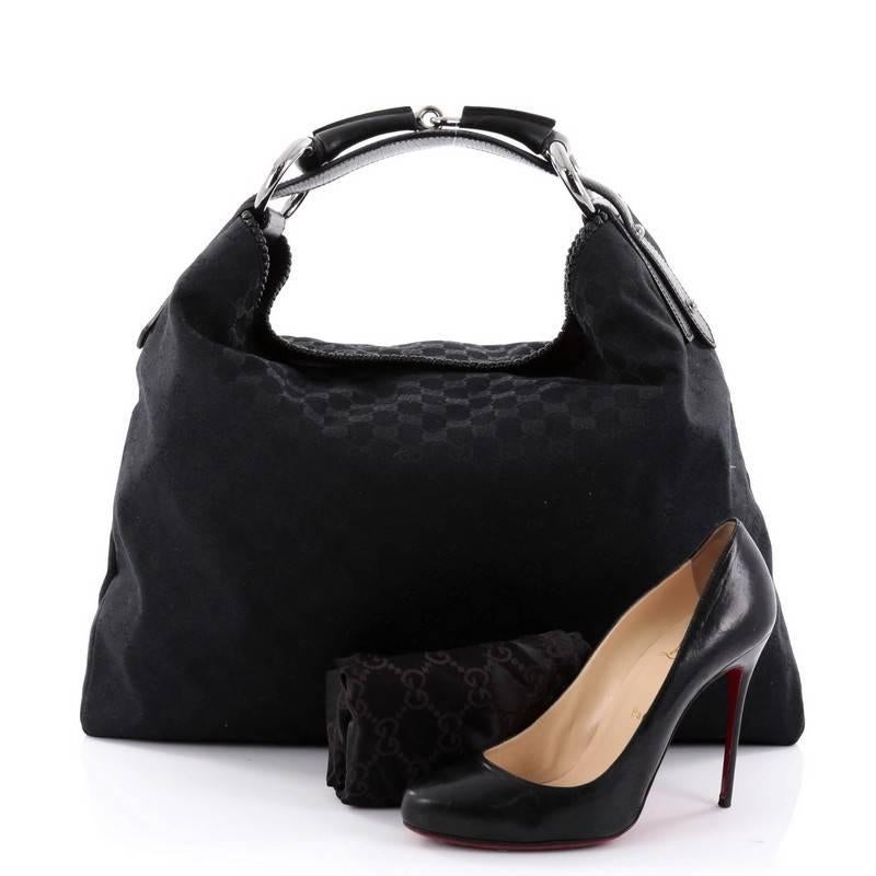 This authentic Gucci Horsebit Hobo GG Canvas Large is an easy to carry, everyday hobo that is both stylish and functional. Crafted in Gucci's black monogram GG canvas, this no-fuss hobo features a signature horsebit top handle strap, edge leather