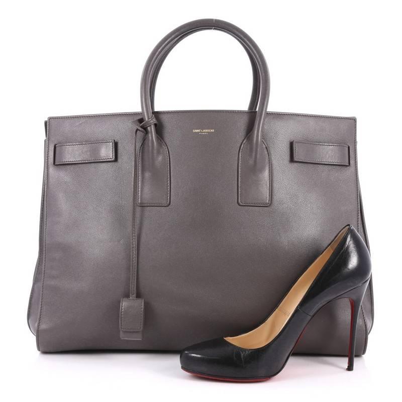This authentic Saint Laurent Sac de Jour Handbag Leather Large is a sleek yet elegant bag synonymous with the brand's classic aesthetics. Crafted from grey smooth leather, this sought-after tote features a gold Saint Laurent stamped signature at the