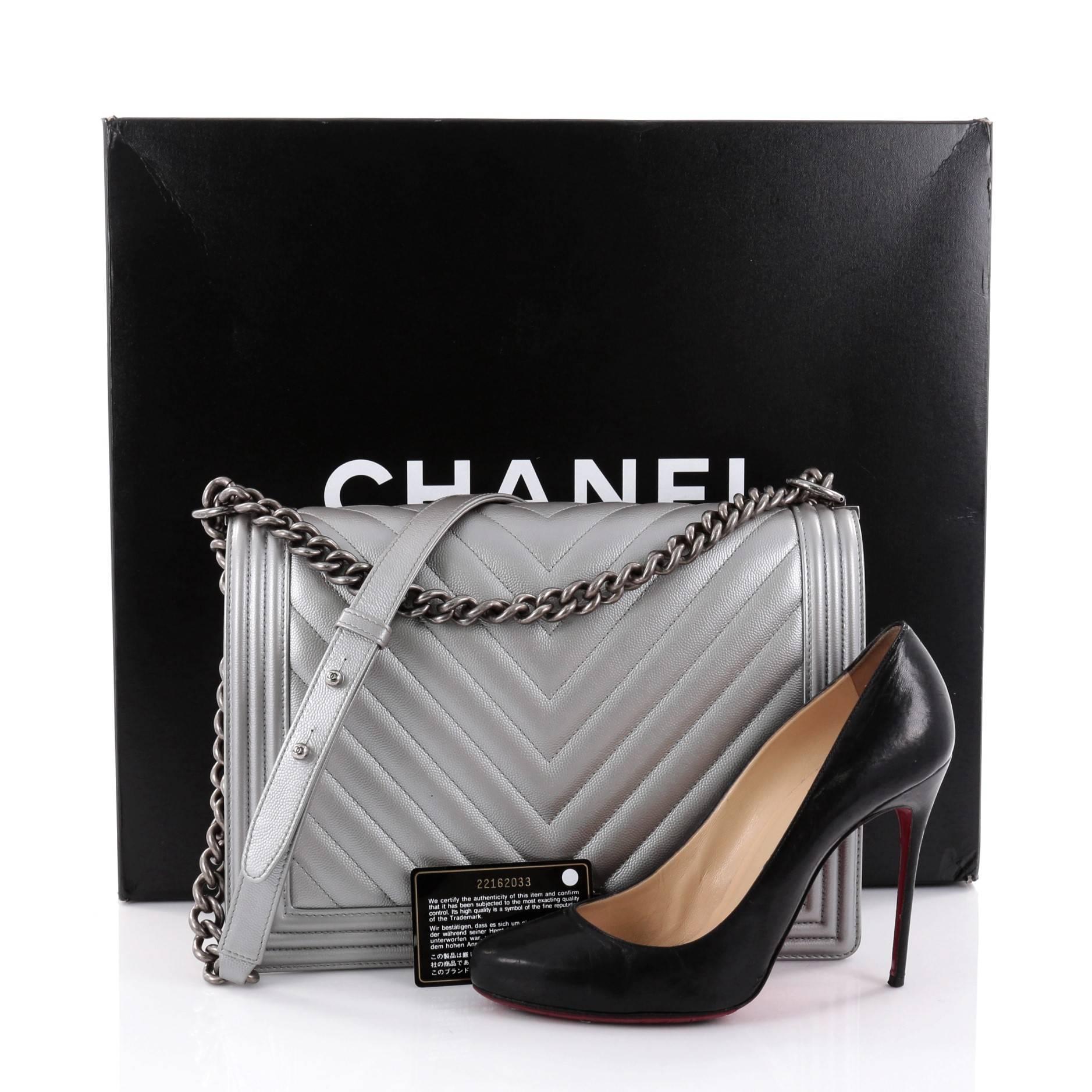 This authentic Chanel Boy Flap Bag Chevron Caviar Large combines classic Chanel craftsmanship with definitive style fit for the contemporary fashionista. Crafted from silver chevron quilted caviar leather with a structured rectangular silhouette,