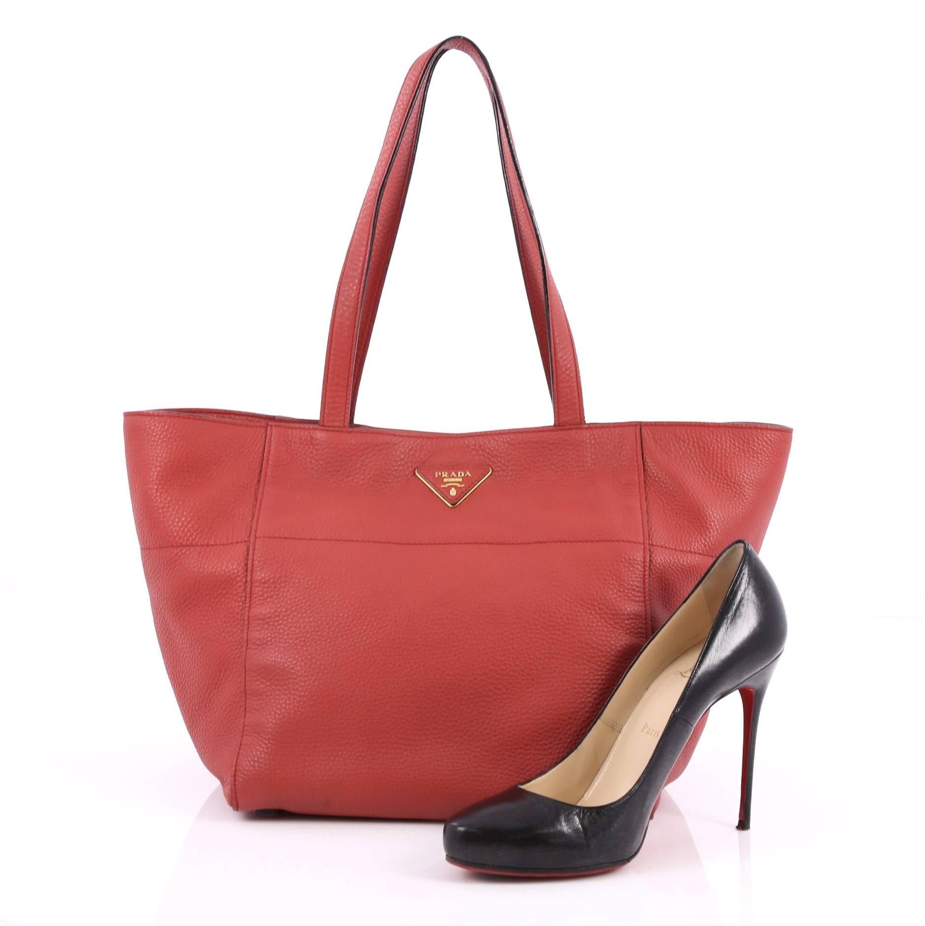 This authentic Prada Open Tote Vitello Daino Small is a chic and stylish everyday bag for casual looks. Crafted from red vitello daino leather, this simple, functional tote features dual-flat leather handles, signature Prada logo, protective base