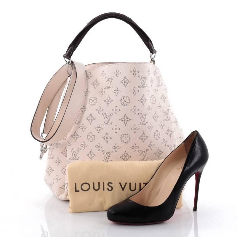 This authentic Louis Vuitton Babylone Handbag Mahina Leather PM presented in the brand's 2015 Collection is a luxuriously chic and modern city hobo made for the modern woman. Crafted from pale pink monogram mahina perforated leather, this stylish