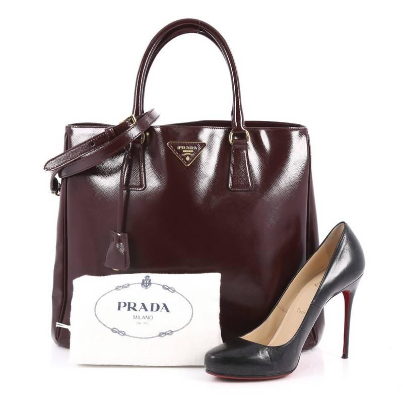 This authentic Prada Convertible Open Tote Vernice Saffiano Leather Large is elegant in its simplicity and structure. Crafted from burgundy vernice saffiano leather, this sturdy and spacious tote features dual-rolled handles, gusseted side with snap