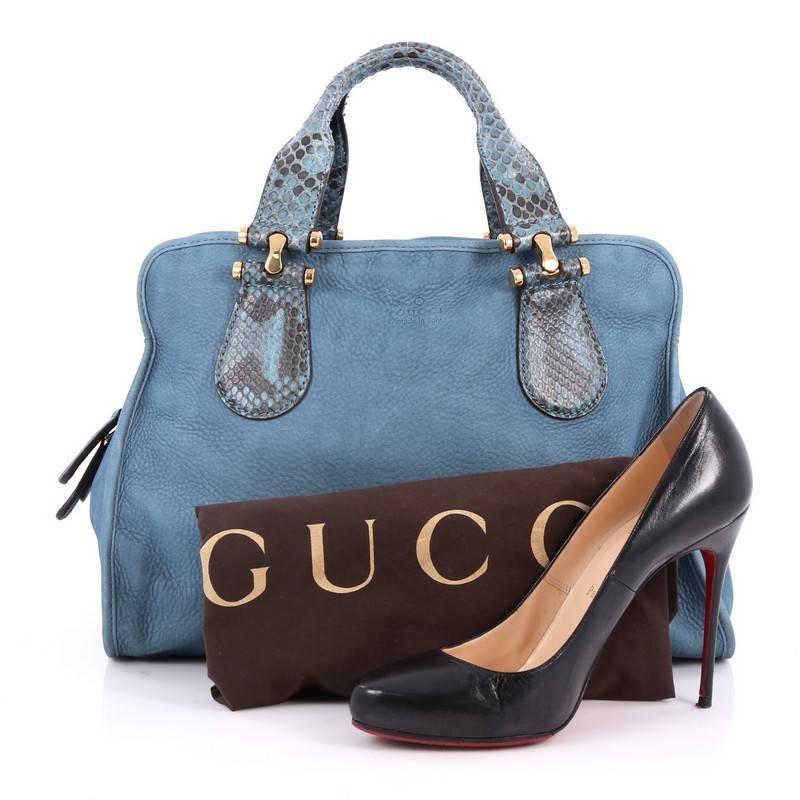 This authentic Gucci Twice Satchel Nubuck with Python is your perfect bag for day or night outs. Crafted from blue nubuck leather with genuine python skin handles, this stylish bag features dual equestrian inspired handles, protective base studs and