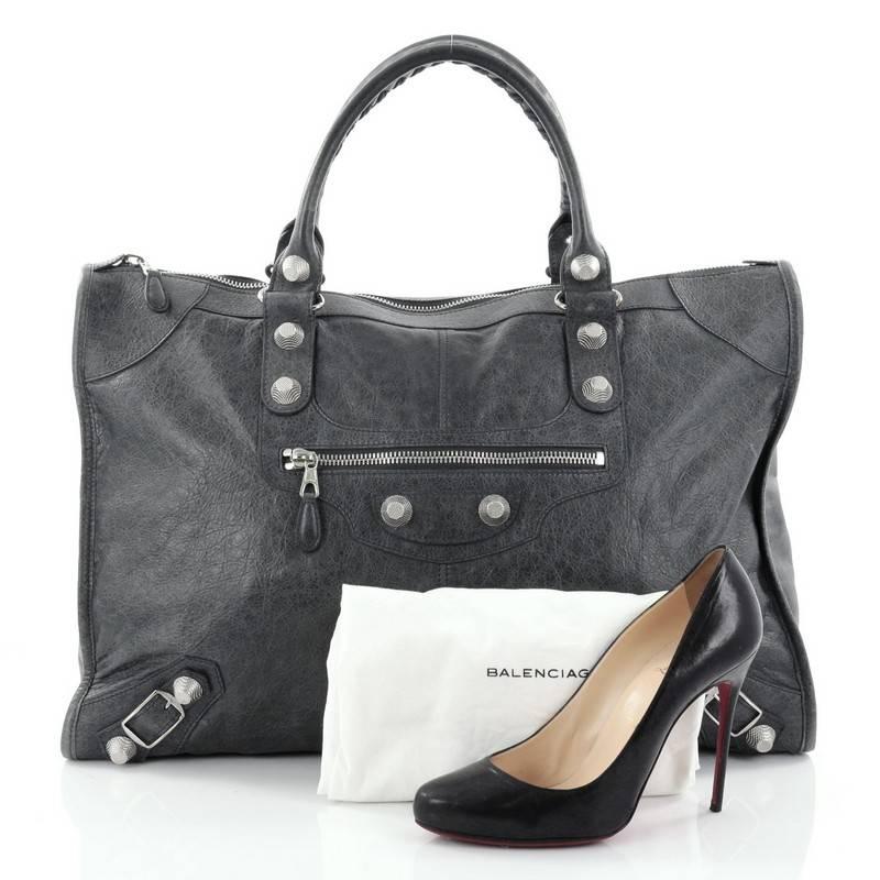 This authentic Balenciaga Weekender Giant Studs Handbag Leather is a stylish and fun accessory made for light travels and weekend getaways. Constructed from grey leather, this lightweight carryall features braided woven handle straps, front zip