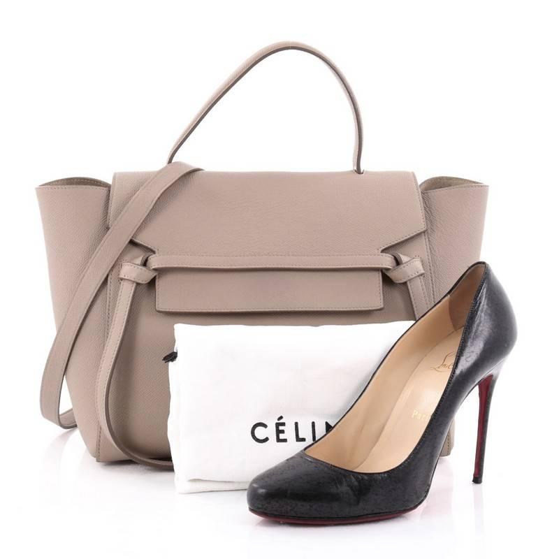 This authentic Celine Belt Bag Textured Leather Mini is sure to make a statement. Crafted from taupe leather, this bold and beautiful bag features expanded wings, looped single top handle, top flap slide closure, knotted ties, zipper pocket at the
