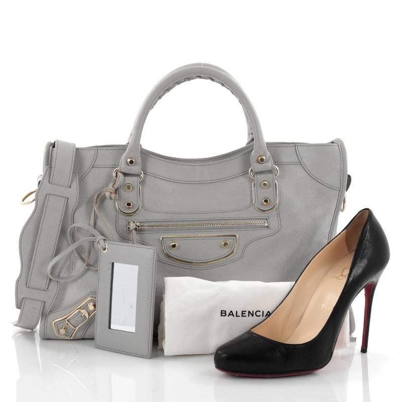 This authentic Balenciaga City Classic Metallic Edge Handbag Leather Medium is for the on-the-go fashionista. Constructed in light grey leather, this popular bag features braided woven handle straps, long fringe details, and iconic Balenciaga