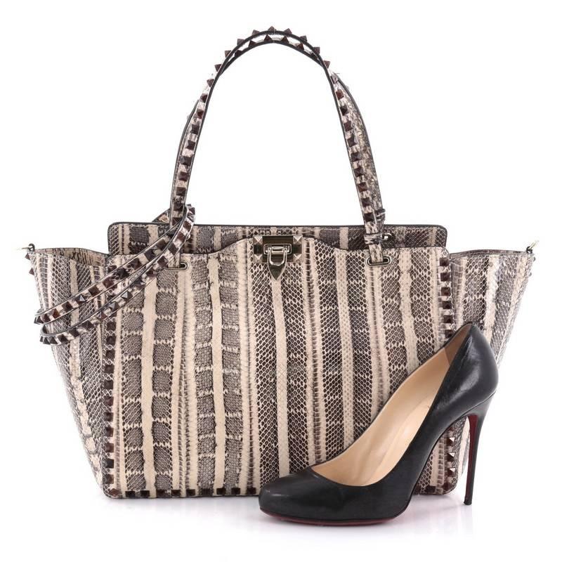 This authentic Valentino Rockstud Tote Python Large is a stylish and iconic bag, one of today's most sought-after styles. Crafted from genuine python, this chic tote features tall dual-flat handles, gold-tone pyramid stud trim details, signature