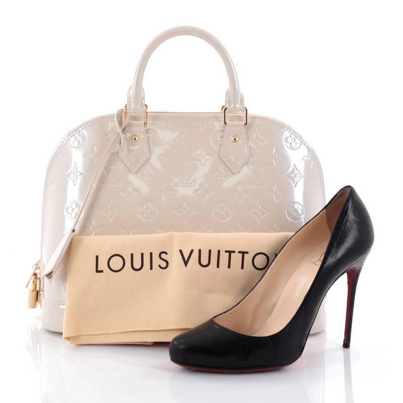 This authentic Louis Vuitton Alma Handbag Monogram Vernis PM is a fresh and elegant spin on a classic style that is perfect for all seasons. Crafted from Louis Vuitton's off-white monogram vernis leather, this dome-shaped satchel features