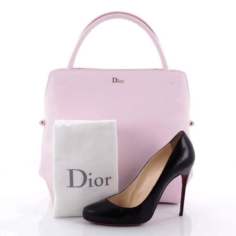 This authentic Christian Dior Top Handle Bag Calfskin Medium takes inspiration from Dior's classic figure 8 bar jacket. Crafted in beautiful pink leather, this impeccably chic bag features a clean and boxy design, dual-rolled handles, side push pin
