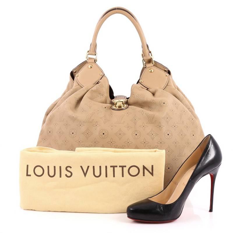 This authentic Louis Vuitton XL Hobo Mahina Leather is sleek and refined in design apt for the modern woman. Crafted from beige monogram perforated mahina leather, this oversized, feminine hobo features dual-rolled handles, buckle and stud details,