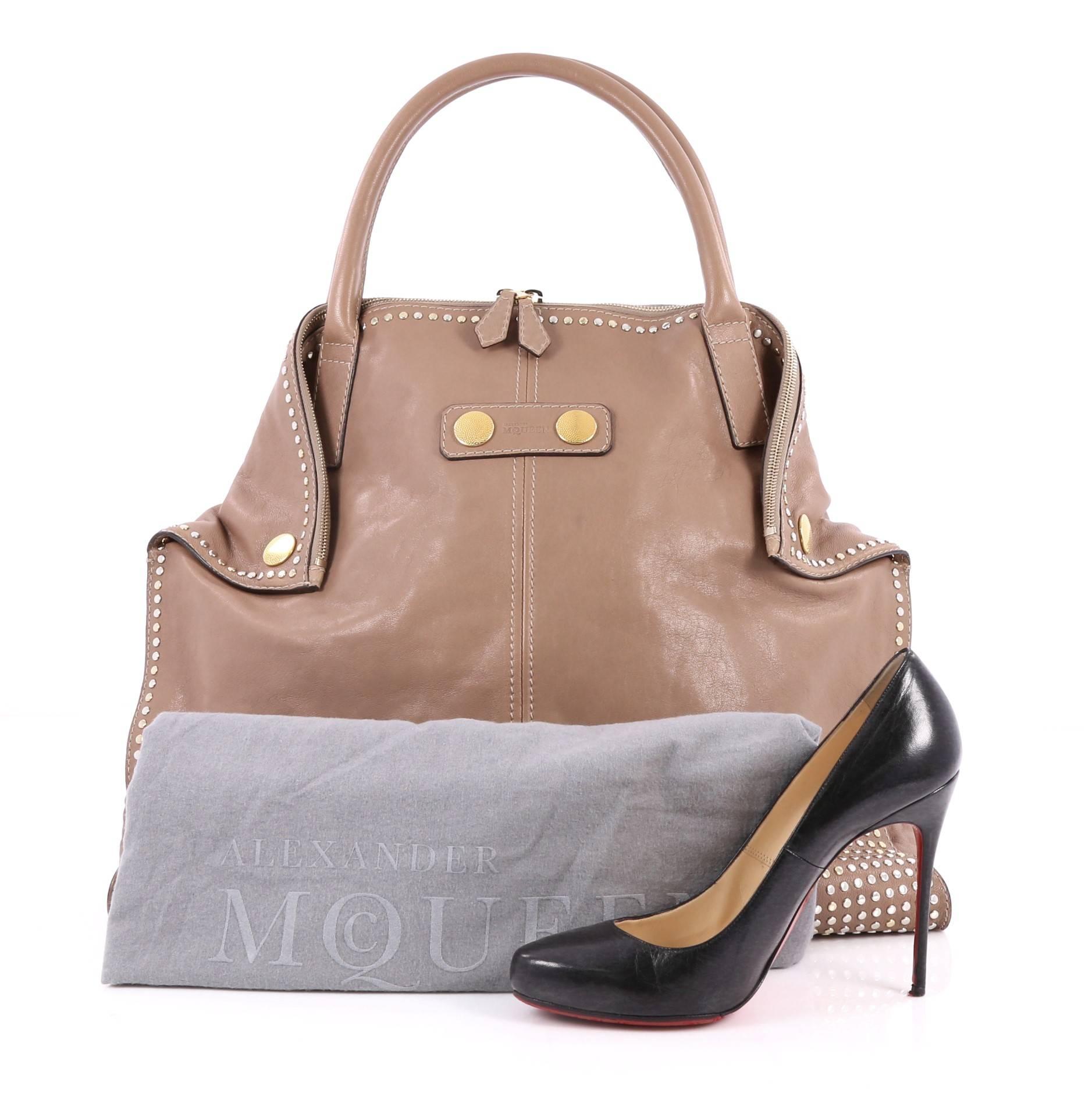 This authentic Alexander McQueen De Manta Tote Studded Leather Large is simple and minimalist in design ideal for work and everyday casual looks. Crafted in taupe leather, this elongated tote features dual-rolled handles, fold-down hidden magnet