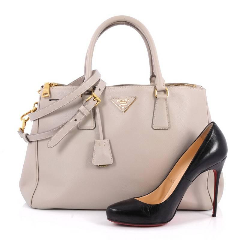 This authentic Prada Double Zip Lux Tote Saffiano Leather Medium is the perfect bag to complete any outfit. Crafted from light grey saffiano leather, this boxy tote features side snap buttons, raised Prada logo, dual-rolled leather handles and