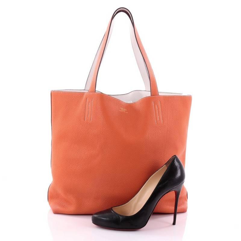 This authentic Hermes Double Sens Tote Clemence 45 combines a simple and functional style from Hermes perfect for everyday use. Crafted from soft luxurious reversible orange and white clemence leather, this versatile tote features dual flat leather