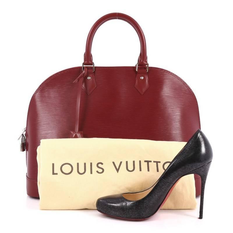 This authentic Louis Vuitton Alma Handbag Epi Leather GM is elegant and as classic as they come. Constructed with Louis Vuitton's signature dark red epi leather, this bag features a structured and dome-like silhouette, dual-rolled leather handles,