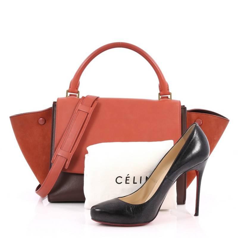 This authentic Celine Bicolor Trapeze Handbag Leather Mini is a modern classic featuring a minimalist design. Crafted with brown and coral leather with suede wings, this Trapeze bag features rolled leather handle, zip back pocket, expanded side