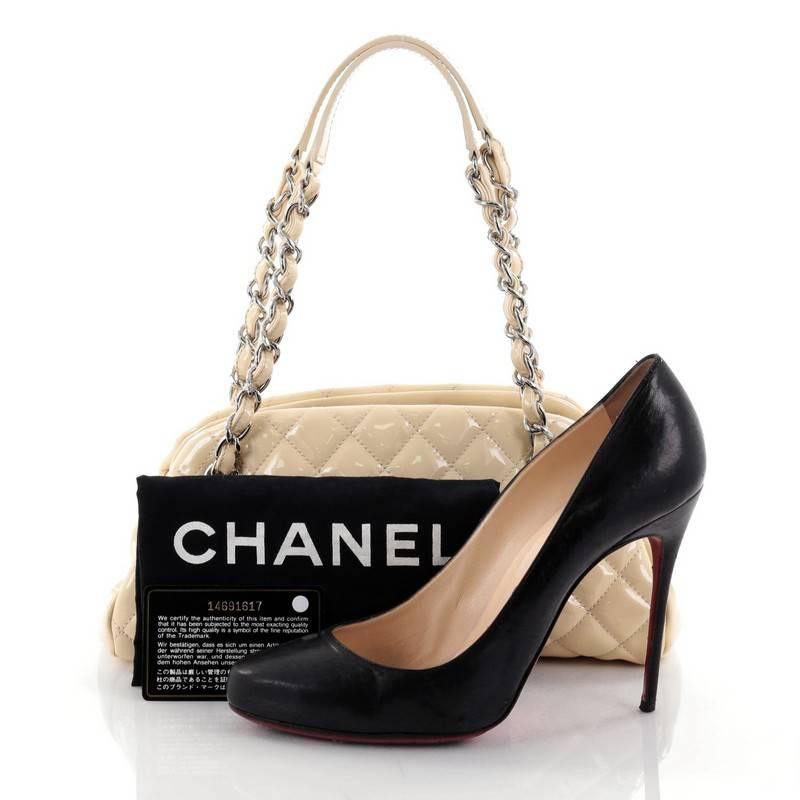 This authentic Chanel Just Mademoiselle Handbag Quilted Patent Small showcases a sleek style that complements any look. Crafted from beige patent leather in Chanel's iconic diamond quilt pattern, this bag features woven-in leather chain straps with
