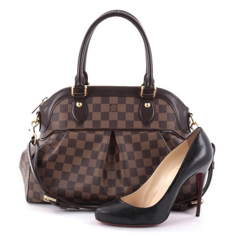 This authentic Louis Vuitton Trevi Handbag Damier PM inspired by the Trevi Fountain is a chic and versatile satchel. Crafted from classic damier ebene coated canvas, this bag features dual-rolled handles, brown leather trims, subtle pleats on front,