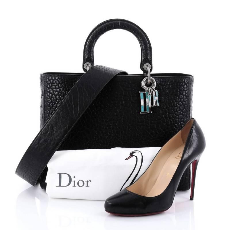 This authentic Christian Dior Lady Dior Handbag Canyon Grained Lambskin Large is an elegant classic bag that every fashionista needs in her wardrobe. Crafted from black grained lambskin leather, this boxy bag features short dual handles with sleek