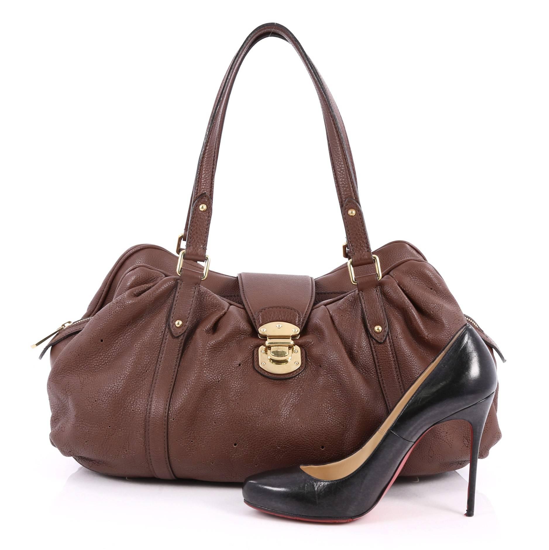 This authentic Louis Vuitton Lunar Handbag Mahina Leather GM is a unique, functional everyday piece for any Louis Vuitton lover. Crafted from brown monogram perforated mahina leather, this feminine tote features a ruched silhouette, dual flat tall