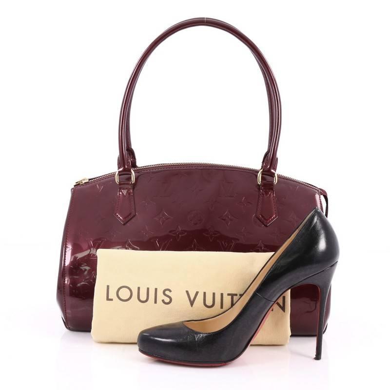 This authentic Louis Vuitton Sherwood Handbag Monogram Vernis GM is a uniquely shaped bag that showcases a modern take to Louis Vuitton's classic design. Crafted from rouge fauviste monogram vernis leather, this structured dome bag features