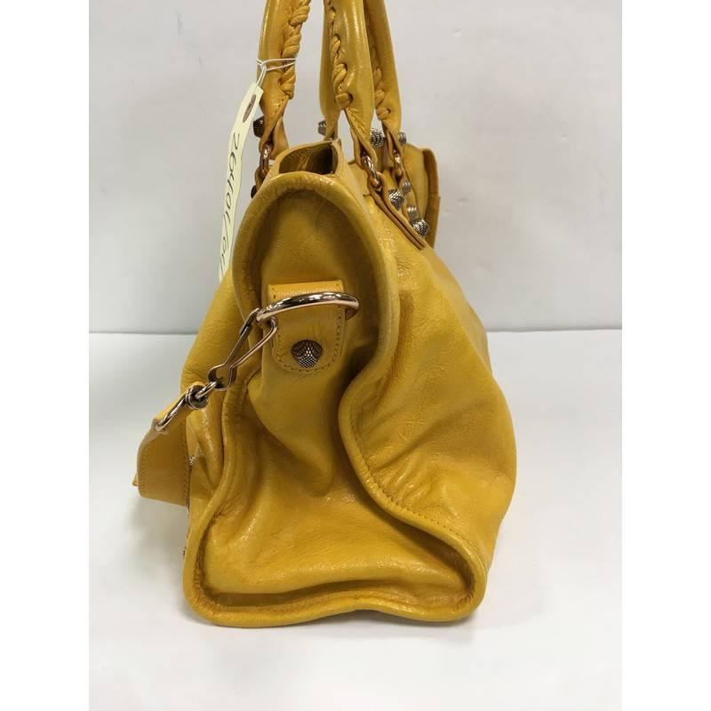 This authentic Balenciaga City Giant Studs Handbag Leather Medium is for the on-the-go fashionista. Constructed from yellow leather, this popular bag features dual braided woven tall handles, exterior front zip pocket, iconic Balenciaga giant studs