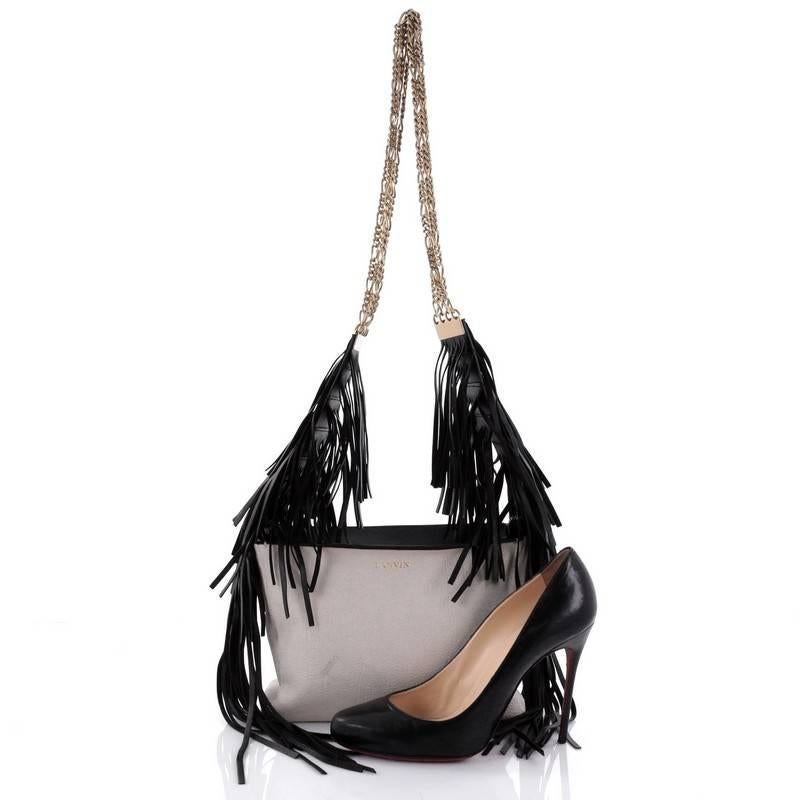 This authentic Lanvin Tribale Shoulder Bag Leather mixes an edgy, boho chic design made for daring fashionistas. Crafted in black and white leather, this shoulder bag features gold chain straps, cascading leather fringes, stamped Lanvin logo and