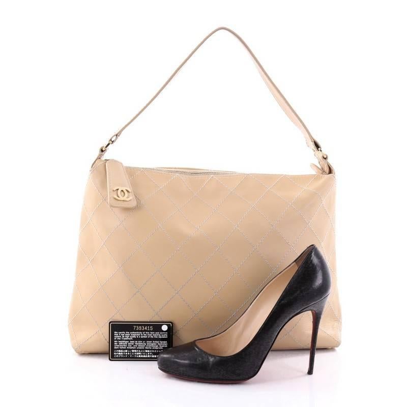 This authentic Chanel Surpique Hobo Calfskin Large is a marvelous bag made for everyday use. Crafted from light beige calfskin leather with surpique-style quilted stitching, this bag features a flat leather shoulder strap, leather zip pull with