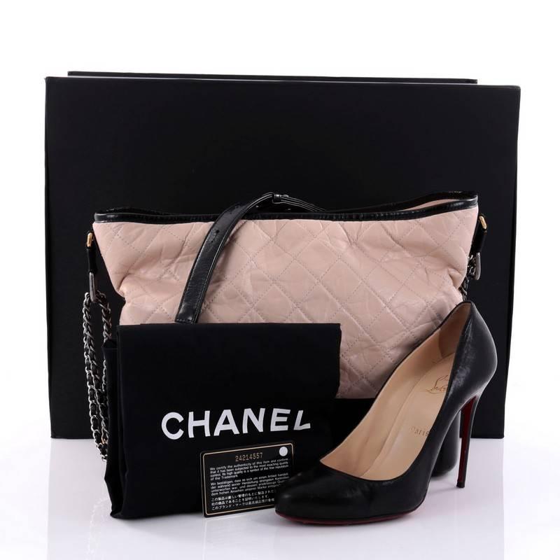 This authentic Chanel Gabrielle Hobo Quilted Aged Calfskin Large displays a luxurious design with timeless modernity. Crafted from quilted nude and black calfskin, this hobo features gradient gold to silver woven-in leather chain with leather pads,