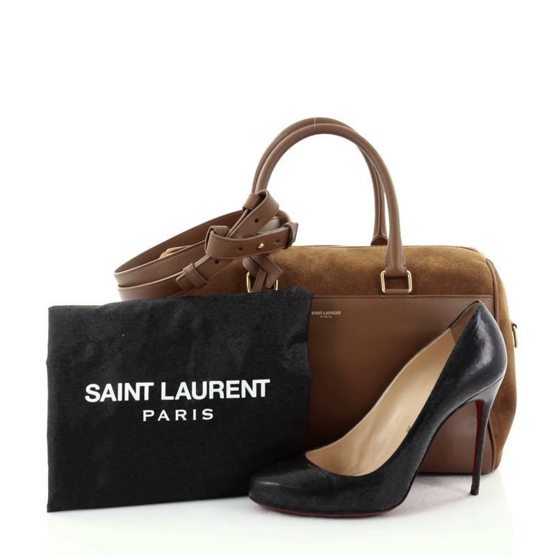 This authentic Saint Laurent Classic Duffle Bag Suede and Leather 6 is a modern and elegant duffle bag to travel in style with. Crafted in brown suede and leather, this alluring bag features dual-rolled leather handles, detachable strap, stamped
