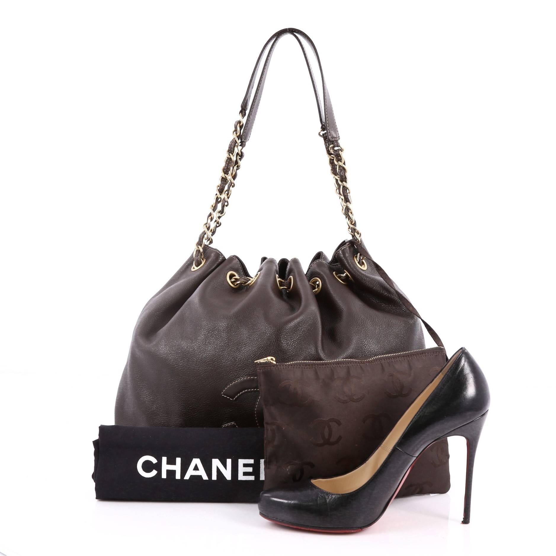 This authentic Chanel Vintage CC Drawstring Chain Shoulder Bag Leather Small is a timeless, elegant bucket bag that is ideal for everyday use. Crafted in dark brown leather, this chic shoulder bag features long gold woven-in leather chain link