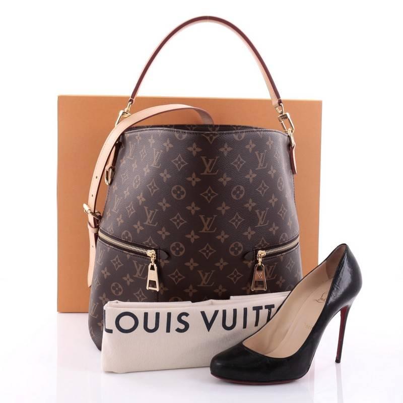 This authentic Louis Vuitton Melie Handbag Monogram Canvas is one of the brand's newest creations and features a fresh take on the classic hobo design. Crafted in brown monogram coated canvas, this bag features a flat leather short handle, a long