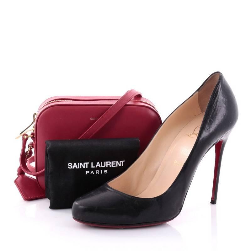 This authentic Saint Laurent Camera Bag Leather Small showcases a minimalist boxy yet chic silhouette perfect for the modern fashionista. Crafted from red leather, this small crossbody bag features a gold stamp Saint Laurent logo at the front, a