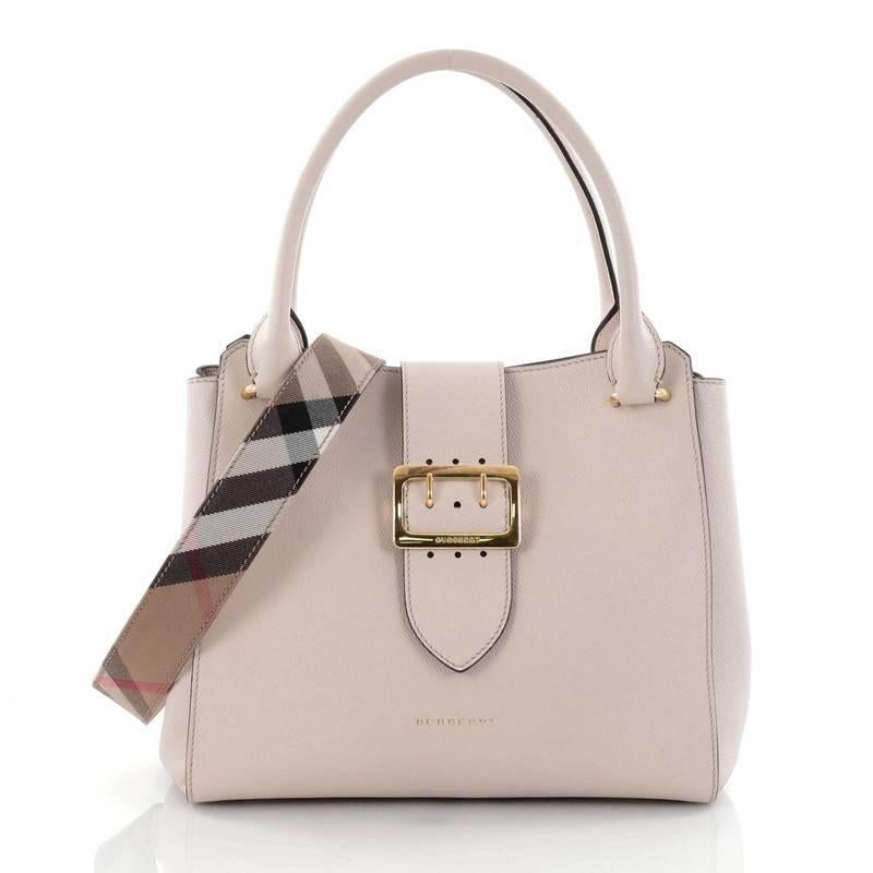 This authentic Burberry Buckle Tote Leather Medium is luxurious and sophisticated in design perfect for all seasons. Crafted from cream leather, this chic bag features dual-rolled leather handles, removable, adjustable house check canvas shoulder