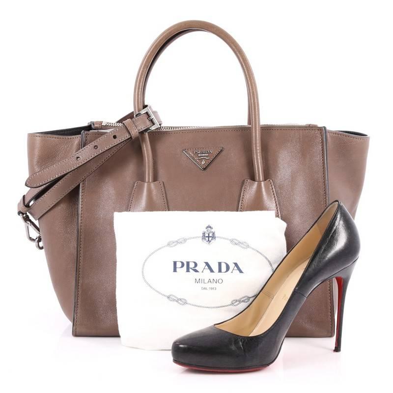 This authentic Prada Twin Pocket Tote Glace Calf Small showcases a sophisticated silhouette balancing modern luxury and style perfect for the on-the-go woman. Crafted from brown glace calf leather, this boxy tote features tall dual-rolled top