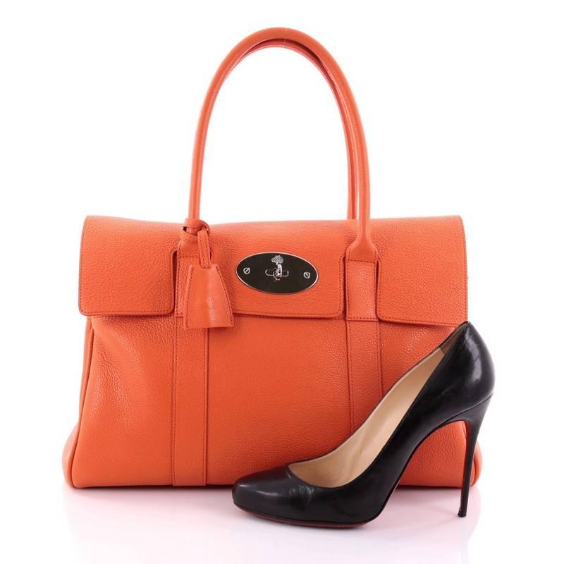 This authentic Mulberry Bayswater Satchel Leather Medium showcases the brand's simple, iconic design made for everyday use. Crafted from orange leather, this industrial-style tote features tall dual-rolled leather handles, signature postman's lock